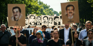 Menschen halten Schilder mit Porträts der NSU Opfer