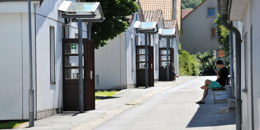 ein junger Mann sitzt vor einer provisorischen Behausung