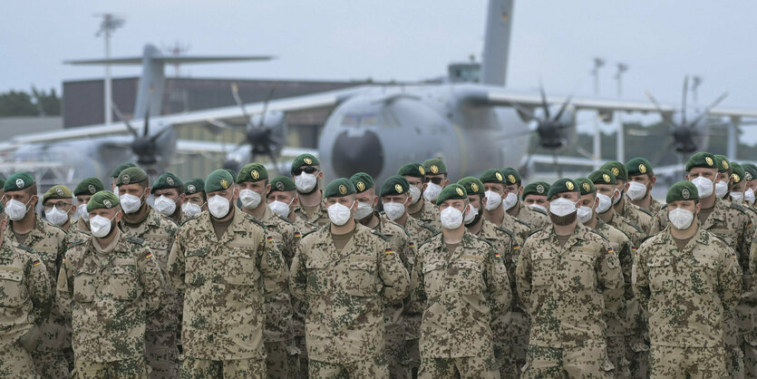 Bundeswehrsoldaten stehen vor einem Flugzeug.