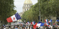 Auf einer Allee in Paris schwenken zahlreiche Menschen Frankreich-Flaggen