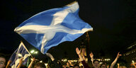 Eine schottische Flagge weht über die Köpfe von Menschen in der Nacht