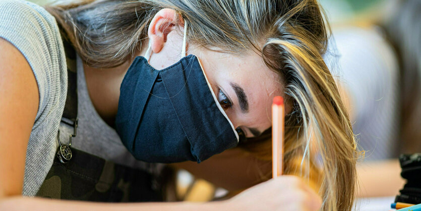 Schülerin mit Maske schreibt