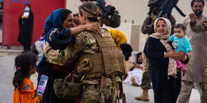 Eine afghanische Frau umarmt dankbar eine US-Soldatin, die ihr geholfen hat, ihre Familie wiederzufinden