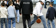 Ein Polizist geht zwischen Kindern, die Ball spielen.