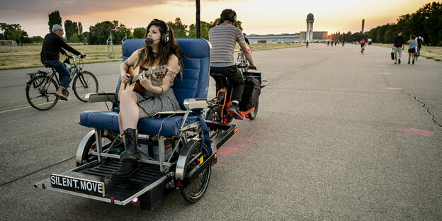Gitarrenspielerin wird von einem Lastenrad gezogen