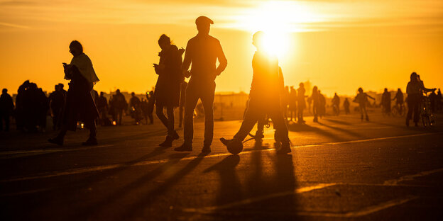 Menschen laufen im Abend-Gegenlicht über das Tempelhofer Feld