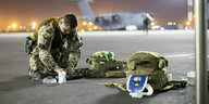 Ein Soldat kniet in Uniform auf dem Boden und packt seine Ausrüstung zusammen
