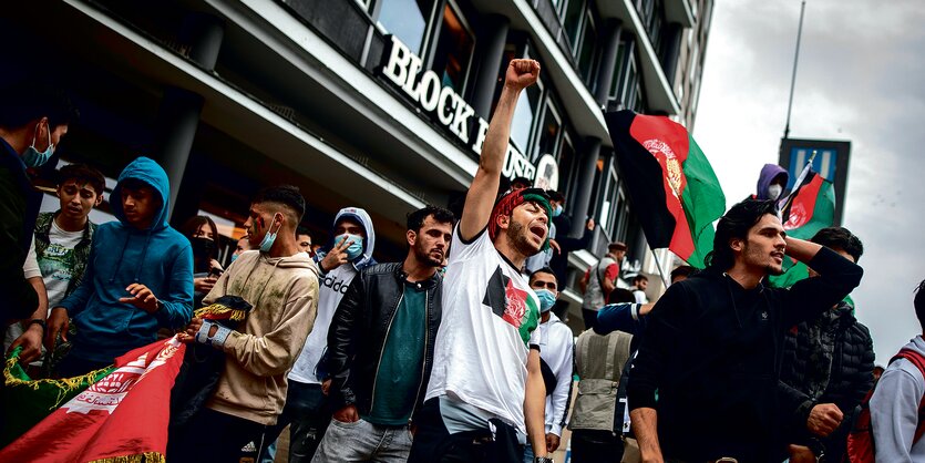 Afghanische Demonstranten ziehen mt Flaggen durch Hamburg. Ein Demonstrant streckt eine Faust in die Luft.