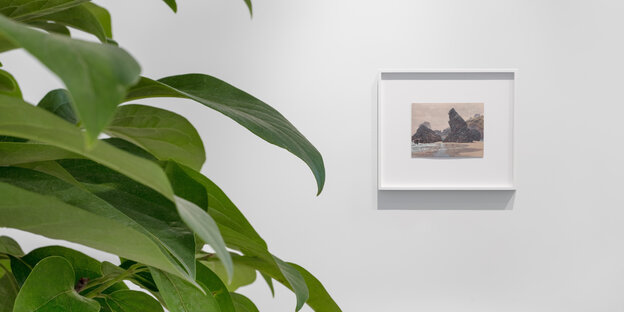 Die Blätter eines Baumes ragen links ins Bild, rechts hinten an der Wand ist ein Gemälde von Maria Loboda zu sehen