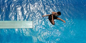 Das Bild zeigt einen springenden Jungen im Schwimmbad.