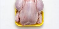 Ein rohes, gerupftes Huhn liegt von Plastikfolie umgeben in einer Styroporschalte.