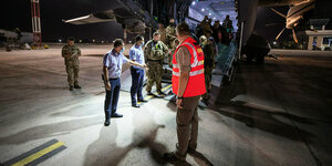 Hilfe für die Geflüchteten beim Aussteigen über der Heckrampe eines Airbus A400M