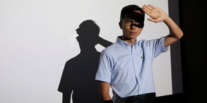 Kiwi Chow hebt die Hand vors Gesicht, hinter ihm sein Schatten