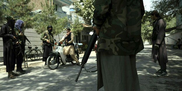 Bewaffnete Talibankämpfer kontrollieren einen Mopedfahrer