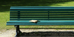 Ein aufgeschlagenes Buch auf einer Parkbank