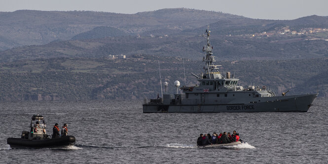 Ein Kriegsschiff vor Geflüchteten in einem kleinen Boot