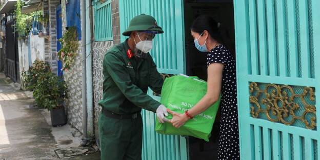 Vietnamesischer Soldat gibt einer Frau eine grüne Tasche mit Essen