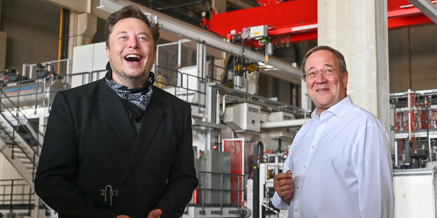 Elon Musk und Armin Laschet lachen bei der Besichtigung des Tesla-Werkes in Grünheide