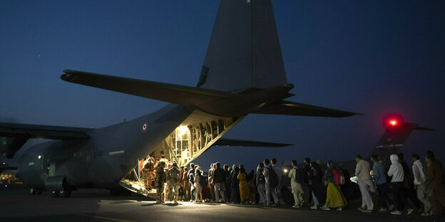 Menschen besteigen bei Nacht ein Militärflugzeug