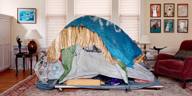 Auf dem Teppich in einem Wohnzimmer steht ein Zelt mit vielen Decken