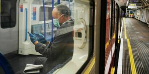 Ein Mann sitzt in der Ubahn in London mit einem Smartphone