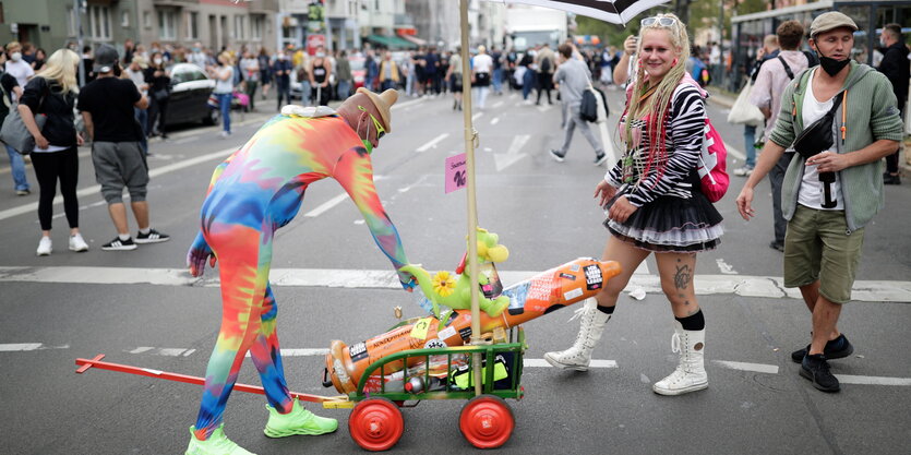 Verkleidete Teilnehmer*innen des Zugs der Liebe ziehen einen Wagen