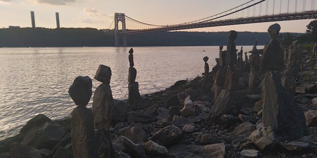 Figuren aus Steinen stehen am Ufer des Hudson River