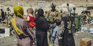Eine Gruppe von Frauen und Kindern stehen vor einem Soldaten