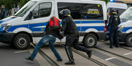 Ein Demonstrant mit Rucksack wird von einem Polizisten weggedrückt