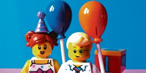 Zwei Plastik-Spielfiguren halten Luftballons in der Hand
