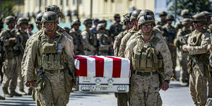 Zwei US-Soldaten tragen einen Sarg, der mit der US Flagge bedeckt ist