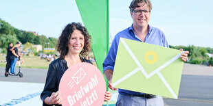 Bettina Jarasch und Michael Keller stehen mit Briefwahlplakaten auf dem Tempelhofer Feld