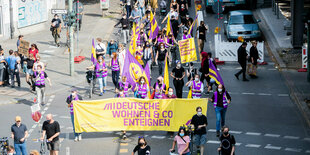 Menschen protestieren auf der Straße mit einem großen Transparent für Enteignung großer wohnungskonzerne