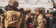 Afghanistan: US-Soldaten stehen hinter einem Zaun,davor Massen an Afghanen am Flughafen von Kabul