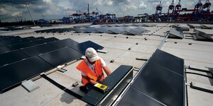 Ein Arbeiter installiert Solarpanelen auf dem Logistikzentrum Altenwerder.