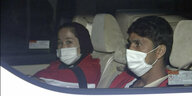 Zwei Sportler mit Mundschutz sitzen in einem Auto