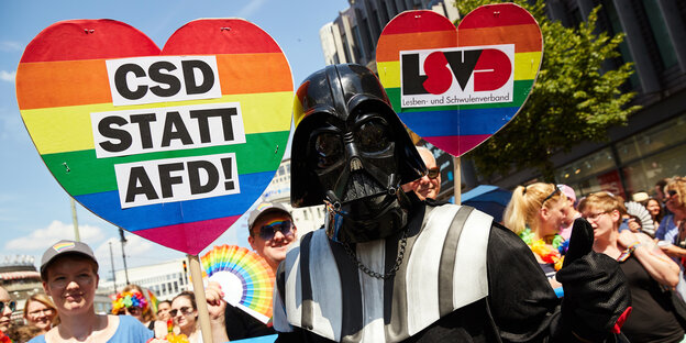 Demonstrant mit Darth-Vader-Maske mit zwei Schildern: CSD statt AFD und LSVD