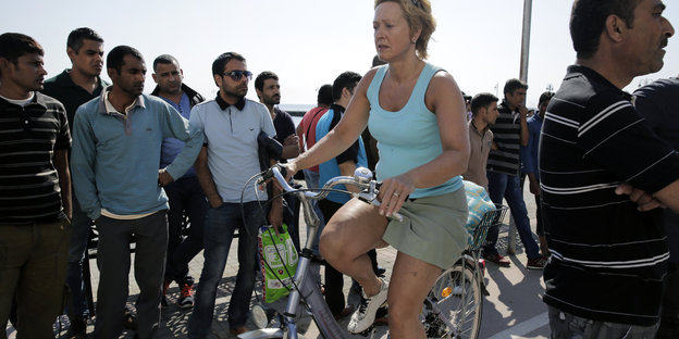 Eine Touristin auf Kos fahren mit dem Rad an Migranten vorbei