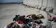 zurückgelassene Kleidungsstücke und Gepäck vor einer Mauer
