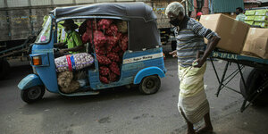 Männer mit Minitrucks und Schubkarren transportieren Lebensmittel