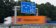 Ein Lastkraftwagen fährt auf der Autobahn A1 in der Nähe der Anschlussstelle Bockel unter einem Autobahnschild entlang.