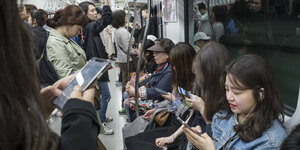 IN einer Ubahn stehen viele Menschen dicht aneinader mit Smartphones in der Hand