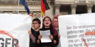 Drei junge Menschen mit Transparenten vor dem Reichstagsgebäude