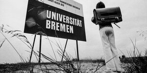 Ein Kind mit Schulranzen steht vor einem Bauschild für die Uni Bremen (Schwarz-Weiß-Bild)