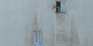 Ein polnischer Fußballfan befestigt eine Fahne an seinem Fenster.
