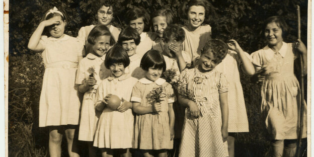 Jüdische Mädchen in einem Kinderheim auf der Wiese, alle stehen in weißen Kleidchen da und schauen in die Kamera. Das Bild ist wahrscheinlich von 1940
