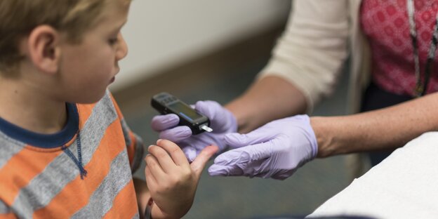 Bei einem Jungen wird mit einem Glucosesensor der Blutzucker kontrolliert.