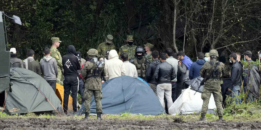 Geflüchtete vor Zelte, die von Unifromierten eingekesselt sind