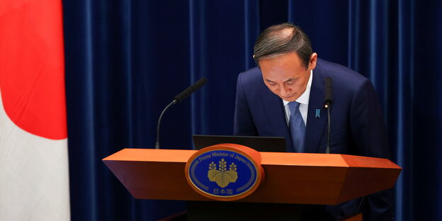 Japans Ministerpräsident verbeugt sich hinter einem Redepult