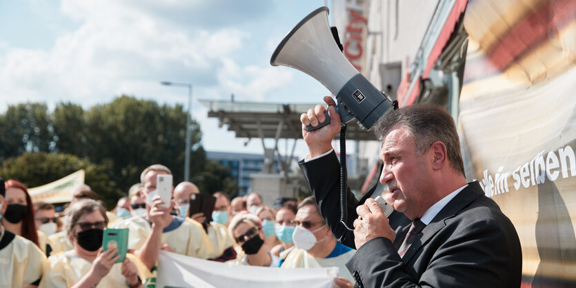 GDL-Chef Claus Weselsky spricht am 11.08.2021 am Ostbahnhof zu streikenden Lokführer:innen und hält ein megafon in der Hand